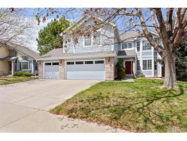 Charming two-story home features a three-car garage, well-maintained lawn, and inviting red door at 9745 Quay Loop, Westminster, CO 80021