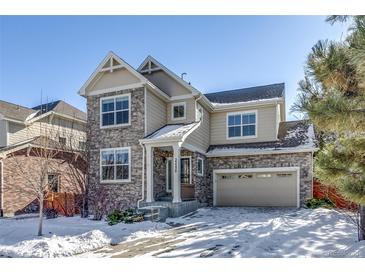 Two-story house with stone and siding exterior, two-car garage, and snowy front yard at 23320 E Berry Ave, Aurora, CO 80016