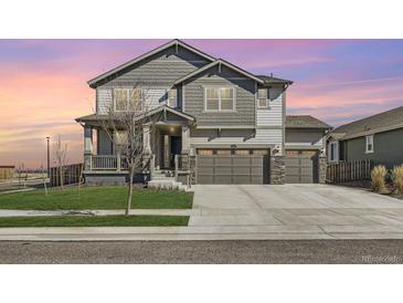 Beautiful two-story home with a three-car garage, stone accents, and a well-maintained lawn at 10992 Xanadu St, Commerce City, CO 80022