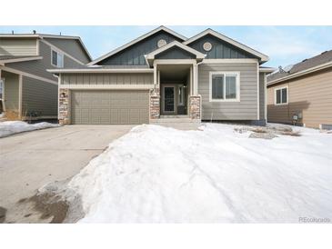 Charming home with a two-car garage, stone accents, and a well-maintained yard partially covered in snow at 762 Tailings Dr, Monument, CO 80132