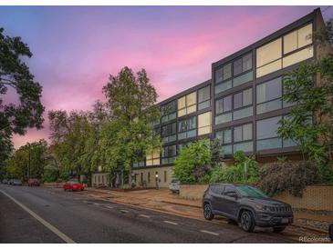 Modern apartment building with large windows and mature trees creating an inviting street view at 1050 N Corona St # 105, Denver, CO 80218