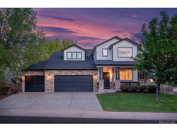 Charming two-story home with a manicured lawn, stone accents, and a spacious three-car garage at dusk at 6488 Tilbury Ave, Firestone, CO 80504