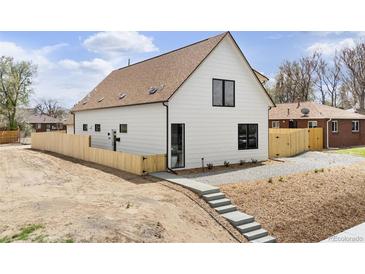 Charming home featuring white siding, a brown roof, black trim windows, and a light wood fence at 3890 N Cook St, Denver, CO 80205
