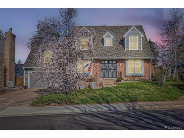 Charming brick home with manicured lawn, blooming tree, and grey roof with dormer windows at 5490 S Jellison St, Littleton, CO 80123