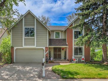 Charming two-story home with a well-maintained front yard and mature trees, featuring mixed siding and brick exterior at 12362 E Vassar Dr, Aurora, CO 80014