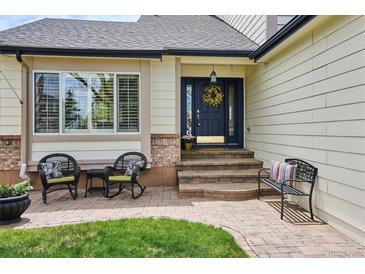 Charming front porch with wicker chairs and decorative wreath on a blue front door at 6836 Edgewood Way, Highlands Ranch, CO 80130