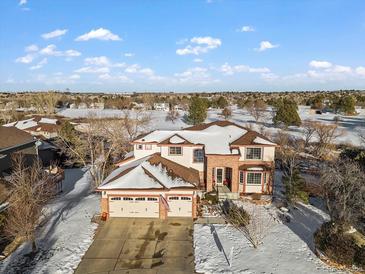 Two-story home with a three-car garage and a snow-covered yard in a residential area at 8932 Tuscany Ln, Highlands Ranch, CO 80130