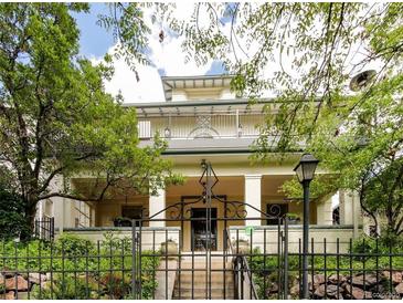 Beautiful two-story home with a large front porch and wrought iron fence at 728 N Ogden St, Denver, CO 80218