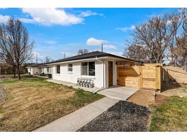 Charming exterior view of a white painted home featuring a well maintained lawn and a modern privacy fence at 3437 N Jackson St, Denver, CO 80205
