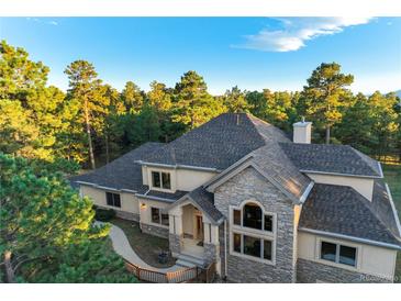 Stunning multi-story home featuring stone accents, mature trees, and a welcoming front entrance at 1220 Scarsbrook Ct, Monument, CO 80132