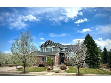 Charming two-story home featuring a brick facade, lush lawn, mature trees, and professional landscaping at 15960 E Aberdeen Ave, Centennial, CO 80016