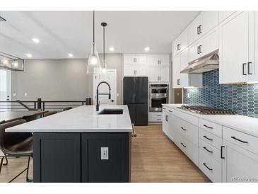 Modern kitchen featuring an island with a sink and stainless steel appliances and lighting at 17233 W 93Rd Pl, Arvada, CO 80007