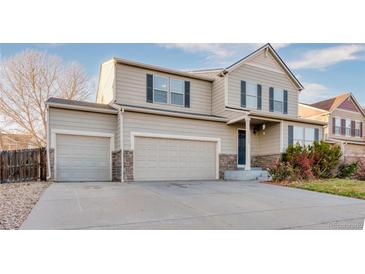 Charming two-story home featuring a three-car garage, landscaped yard, and classic architectural details at 10049 Granby Dr, Commerce City, CO 80022