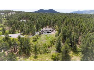 Expansive property featuring a house nestled among dense trees with mountain views at 1988 Lake Dr, Larkspur, CO 80118