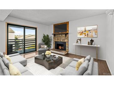 Cozy living room with a stone fireplace and a sliding door to a balcony with plenty of natural light at 7665 E Eastman Ave # D304, Denver, CO 80231