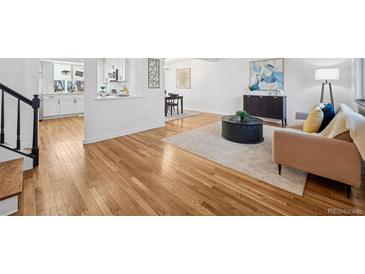 Bright living room with hardwood floors, stylish furniture, and a view into the kitchen at 6675 S Apache Dr, Littleton, CO 80120