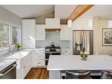 Bright kitchen with white cabinets, stainless steel appliances, a farmhouse sink and an island with counter seating at 780 Utica Ave, Boulder, CO 80304