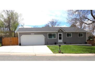 Charming single-story home with gray siding, a white garage door, and a well-manicured front yard at 19038 E Girard Ave, Aurora, CO 80013
