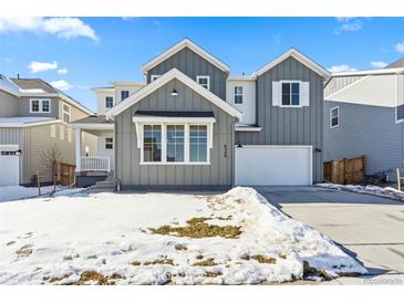 Two-story house with gray siding, white garage door, and snowy front yard at 9349 Russell Cir, Arvada, CO 80007