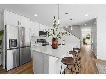 Modern kitchen features stainless steel appliances, white cabinetry, and a large island with stylish seating at 1337 N Alton St, Aurora, CO 80010