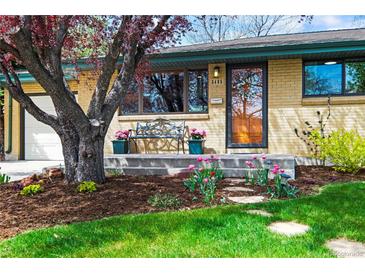 Charming brick home featuring a bench on the porch and a beautifully landscaped front yard with colorful flowers at 5485 S Lakeview St, Littleton, CO 80120