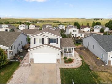 Charming two-story home featuring a covered porch, attached garage, and well-manicured landscaping at 7720 Brown Bear Way, Littleton, CO 80125