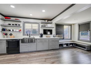 Modern kitchen featuring stainless steel sink, gray cabinets, open shelves, and wood-look flooring at 2226 Fulton St, Aurora, CO 80010