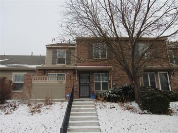 Inviting two-story townhome with brick facade, gray shutters, snowy landscaping, and secure entry steps at 581 Alton Way # B, Denver, CO 80230