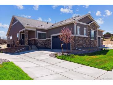 Inviting home featuring a stone and siding exterior, well-manicured lawn, and a paved driveway leading to a two-car garage at 12820 Inca St, Westminster, CO 80234