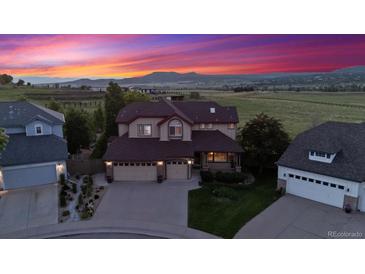 Stunning two-story home with a three-car garage, mature landscaping, and mountain views at sunset at 4099 Starflower Rd, Castle Rock, CO 80109