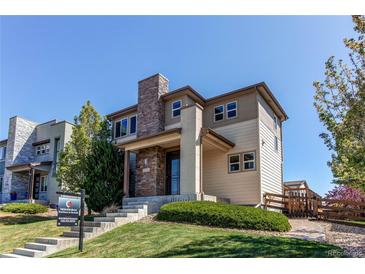 Inviting two-story home featuring stone accents, manicured lawn, and a welcoming front entrance at 10152 Southlawn Cir, Commerce City, CO 80022