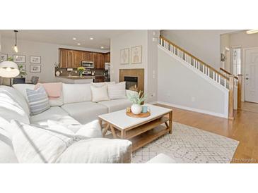 Bright living room features a fireplace, hardwood floors, and access to an open kitchen and staircase at 11886 E Fair Ave, Greenwood Village, CO 80111