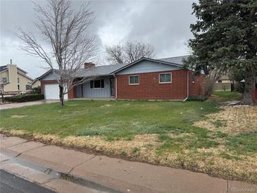 Charming single-story brick home with a well-maintained lawn and attached garage, perfect for suburban living at 1654 Longbranch St, Strasburg, CO 80136