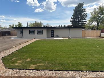 Modern home showcasing a well-manicured lawn and neutral exterior against a backdrop of a partly cloudy sky at 9950 W 17Th Ave, Lakewood, CO 80215