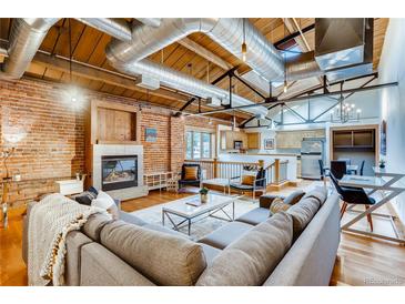 Bright living room featuring exposed brick, wooden ceiling, ductwork, fireplace, and comfortable seating arrangement at 1465 S Pearl St # 6, Denver, CO 80210