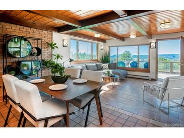 Bright living area featuring wood beam ceiling, tile floors, and large windows offering picturesque mountain views at 21868 Mountsfield Dr, Golden, CO 80401
