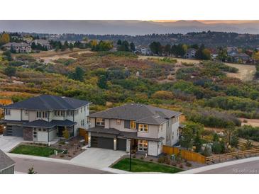 Beautiful two-story home with an attached three-car garage and a meticulously manicured lawn at 6405 Kenzie Cir, Castle Pines, CO 80108