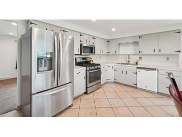 Bright kitchen features stainless steel appliances, ample cabinet space and tile flooring at 12734 Anhawa Ave, Longmont, CO 80503