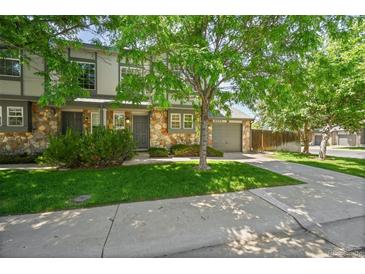Attractive home exterior with stone accents, a well-manicured lawn, and a two-car garage at 10223 Vine Ct, Thornton, CO 80229