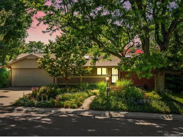 Charming ranch home featuring mature trees, beautiful landscaping, and a welcoming covered porch at 1985 Union St, Lakewood, CO 80215
