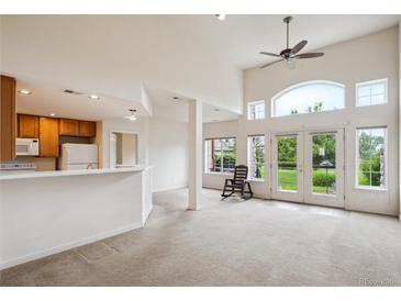 Bright living room featuring high ceilings, a ceiling fan, and sliding glass doors to the outdoor space at 10725 Eliot Cir # 102, Denver, CO 80234