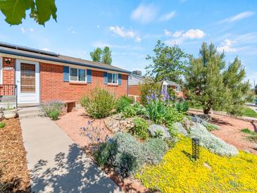 Brick home featuring a beautifully landscaped front yard with colorful flowers and mature trees at 4163 S Decatur St, Englewood, CO 80110