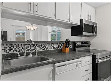 A well-maintained kitchen with updated appliances and black and white tile backsplash at 3021 S Ursula Cir # 102, Aurora, CO 80014