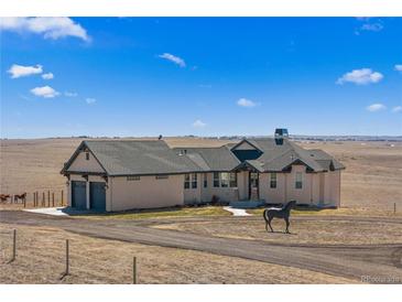 Stunning stucco home with a circular driveway and a horse statue on a vast, open landscape at 7600 Patrick Trl, Elizabeth, CO 80107