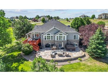 Expansive backyard featuring a stone patio with outdoor seating, hot tub, grill, and a charming raised deck at 9576 E 147Th Pl, Brighton, CO 80602