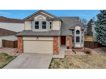 Charming two-story home with a brick-accented garage, bay window, and red front door at 5075 Weeping Willow Cir, Highlands Ranch, CO 80130