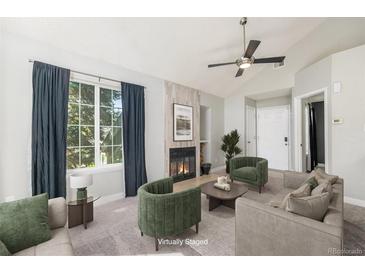 Staged living room features a gas fireplace, large picture window, and modern decor at 4076 S Carson St # H, Aurora, CO 80014