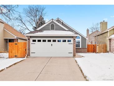 Gray house with white garage door and wooden fence, snow on the ground at 12844 W Cross Dr, Littleton, CO 80127