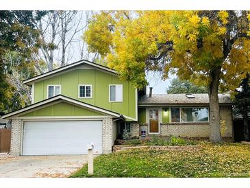 Charming two-story home with a brick and siding exterior, a large front yard, and mature trees at 11237 W 59Th Ave, Arvada, CO 80004