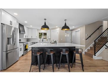 Modern kitchen with a large center island, stainless steel appliances, and stylish pendant lighting at 8334 Allison Ct, Arvada, CO 80005